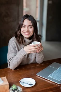 a woman sitting at a table holding a coffee cup