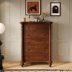 a chest of drawers in a room with pictures on the wall and lamp next to it