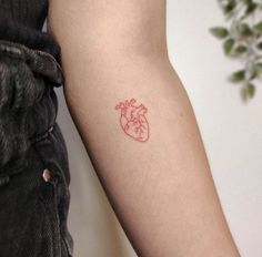 a small red heart tattoo on the left arm by a woman's arm,