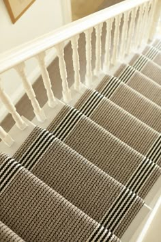 the stairs are lined with beige and black striped carpet