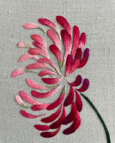 a close up of a flower on a piece of cloth with some pink and red flowers in the middle