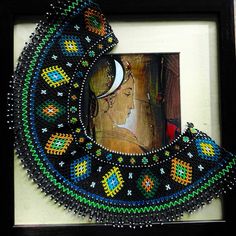 an artistic painting with beads and bead work in a black frame on the wall