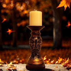 a lit candle sitting on top of a table surrounded by leaves