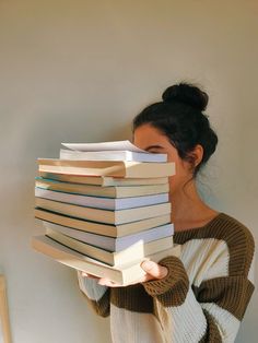 a woman holding a stack of books in front of her face