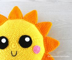 a crocheted sunflower with big eyes on a white wooden background, close up