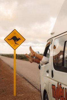 a person sitting in the drivers seat of a van next to a yellow kangaroo sign