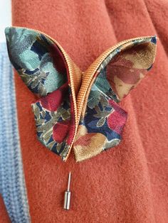 a close up of a bow tie on top of a red jacket with blue and pink flowers