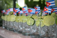 a row of shot glasses filled with limes and flags