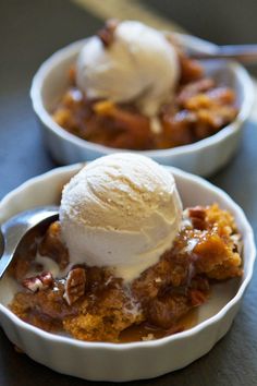 a white bowl filled with ice cream and fruit cobbler dessert on top of a table