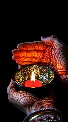 a person holding a bowl with a lit candle in it's palm and hands