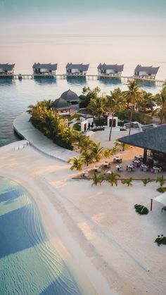 an aerial view of a resort on the beach with palm trees and water in the background