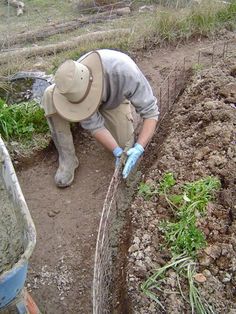 a man wearing a hat and gloves is digging in the dirt with a garden net