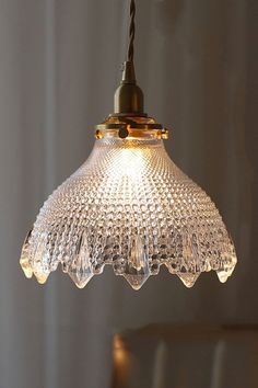 a glass light hanging from a ceiling in a room with white walls and flooring