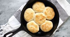 a cast iron skillet filled with biscuits on top of a white and gray towel