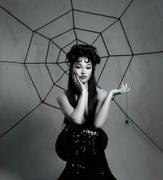 a black and white photo of a woman with her hands on her face in front of a spider web