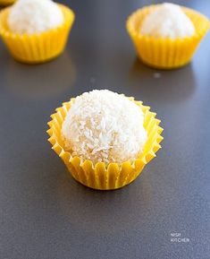 four cupcakes sitting on top of a table covered in white frosting and coconut