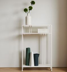 a white shelf with vases and plants on it