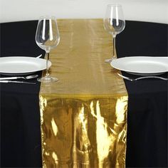 two wine glasses sitting on top of a table next to white plates and silverware