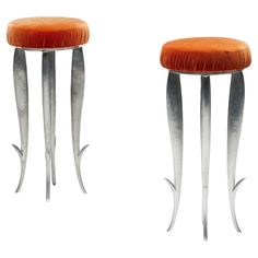 two stools with metal legs and orange velvet seat cushion on each side, one in the