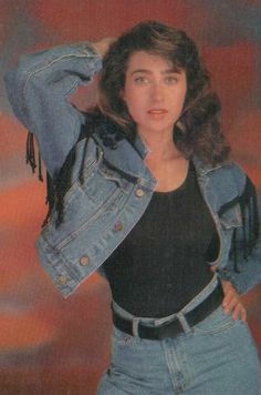 an old photo of a woman wearing a jean jacket and black top with fringes