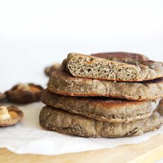 a stack of food sitting on top of a wooden cutting board next to mushrooms and nuts