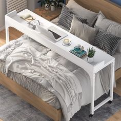 a bed sitting next to a white table on top of a wooden floor