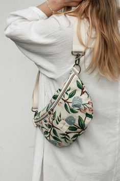 a woman wearing a white shirt and carrying a floral purse with her hand on her shoulder