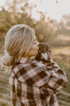 a woman holding a small dog in her arms and looking at the camera while she is outside