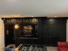 a living room filled with furniture and a fire place in front of a sign that reads magers tavern