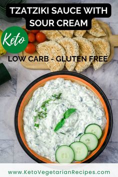 a bowl filled with cucumber and cream sauce next to sliced bread on a cutting board