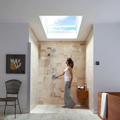 a woman is standing in the shower with her hand on the faucet and looking up at the skylight