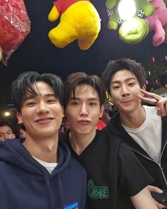 three young men standing next to each other in front of stuffed animals hanging from the ceiling