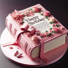 a pink birthday cake decorated with flowers and a book