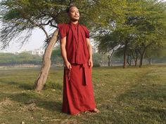 a man standing next to a tree in a field