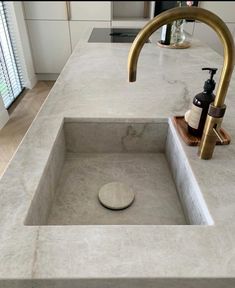 a bathroom sink with a gold faucet and soap dispenser