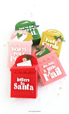 four different colored mail boxes sitting on top of a white surface with the words letters to santa written on them