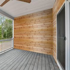 an empty porch with wooden walls and ceiling fan