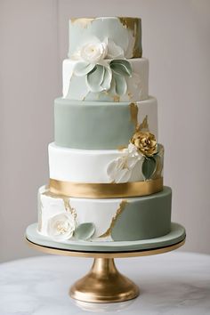 a three tiered wedding cake with flowers on the top and gold trimmings