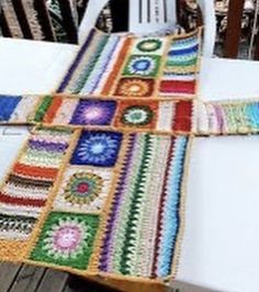 a multicolored crocheted blanket sitting on top of a white tablecloth