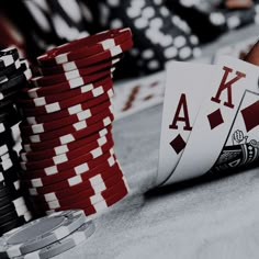 a stack of poker chips sitting on top of a table next to stacks of playing cards