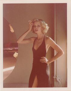 a woman in a black dress standing next to a mirror