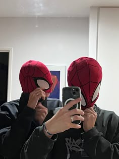 two people wearing spider - man masks taking a selfie in front of a mirror