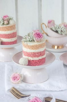 there are three cakes on the table with pink flowers and silverware next to them