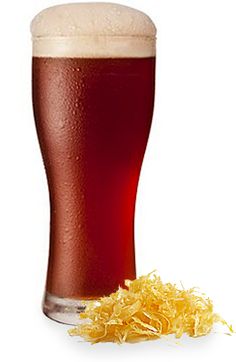 a tall glass filled with beer next to some shredded up yellow paper on a white background