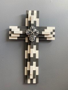 a wooden cross hanging on the wall in front of a gray wall with black and white squares