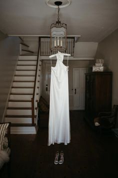 a white dress hanging from a light fixture in a living room next to a stair case