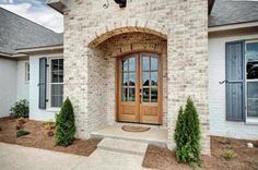 the front entrance to a home with two large doors and three windows on each side