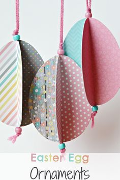 three colorful paper easter eggs hanging from strings on a white wall with polka dotes