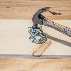 an old hammer and chain sitting on top of a piece of wood