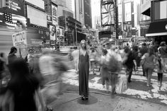 a black and white photo of people crossing the street in times square, new york city